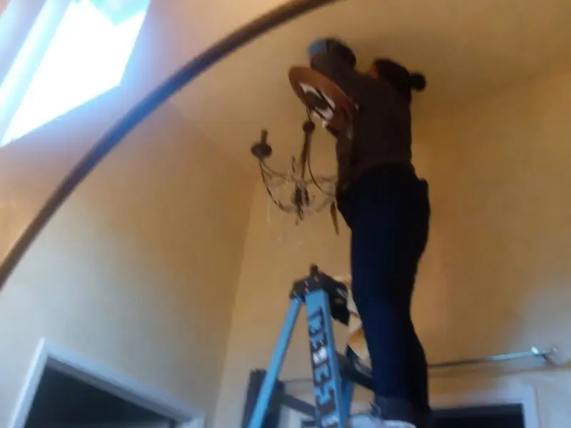 Electrician installing a chandelier in a Nibley residence